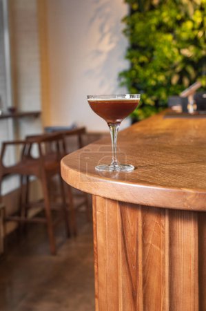 Téléchargez les photos : Espresso martini. Cocktail dans un verre sur un support en bois moderne - en image libre de droit