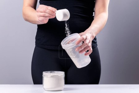 Woman makes a collagen mixture in a mixing glass. Sports nutrition: drink with protein