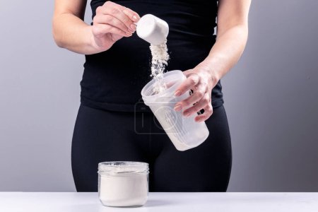 Woman makes a collagen mixture in a mixing glass. Sports nutrition: drink with protein