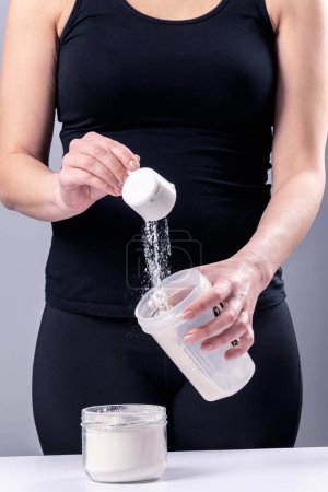 Photo for Woman makes a collagen mixture in a mixing glass. Sports nutrition: drink with protein - Royalty Free Image