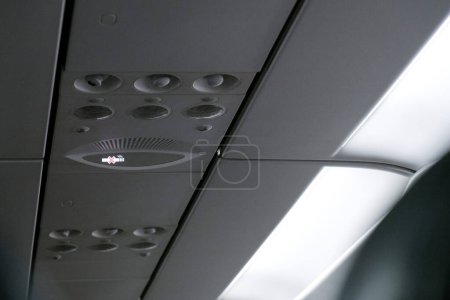 no smoking sign light up on ceiling of airplane cabin above passenger seat that mean cigarette is prohibited in fligh