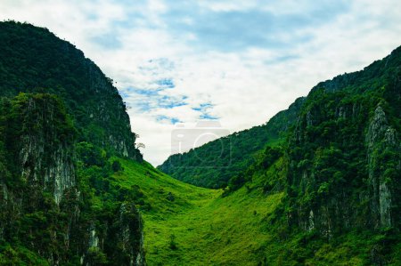 Téléchargez les photos : Passage vert entre deux montagnes dans un ciel nuageux - en image libre de droit
