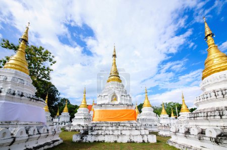 many pagodas in Thai Buddhist temple with cloudy sky