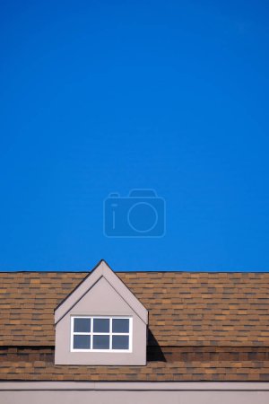 Foto de Techo naranja de la casa con marco de ventana blanca en el cielo claro azul oscuro - Imagen libre de derechos
