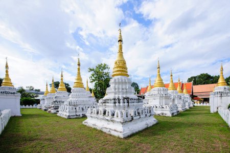 many pagodas in Thai Buddhist temple with cloudy sky
