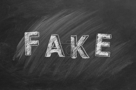 Photo for The word FAKE written in chalk on a blackboard. Information and disinformation concept. Fake news. Hand drawn illustration. - Royalty Free Image