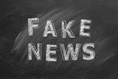 Photo pour The word FAKE NEWS written in chalk on a blackboard. Information and disinformation concept. Hand drawn illustration. - image libre de droit