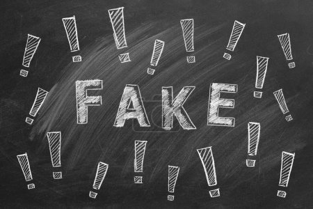 Photo for The word FAKE and exclamation marks written in chalk on a blackboard. Information and disinformation concept. Fake news. Hand drawn illustration. - Royalty Free Image