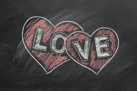 Foto de Dos corazones y la palabra AMOR están dibujados en la pizarra. San Valentín, amor, concepto de compasión - Imagen libre de derechos