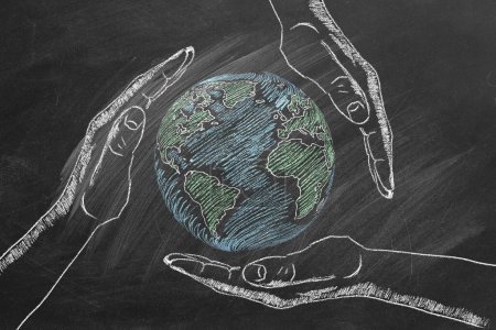 Photo for Rotating globe with male palms hand drawn in chalk on a school blackboard. Save our planet. - Royalty Free Image