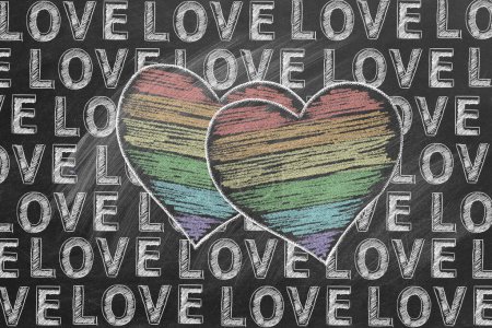Foto de Dos corazones en colores arcoíris esbozados en tiza y la palabra AMOR se repite en toda la imagen en una pizarra. Derechos LGBT, LGBTQIA y concepto de igualdad de género. El mes del orgullo. Declaración de amor. - Imagen libre de derechos