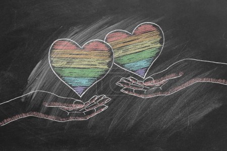 Foto de Dos manos femeninas con corazones de arco iris. Derechos LGBT, LGBTQIA y concepto de igualdad de género. El mes del orgullo. Declaración de amor, aceptación de sentimientos, dar amor. - Imagen libre de derechos