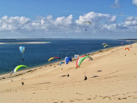 Photo for People paragliding at the Great Dune of Pilat, Arcachon Basin, Nouvelle Aquitaine, France. - Royalty Free Image