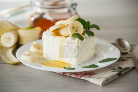 Téléchargez les photos : Portion de lait caillé maison avec tranches de banane et miel, avec menthe dans une assiette. - en image libre de droit