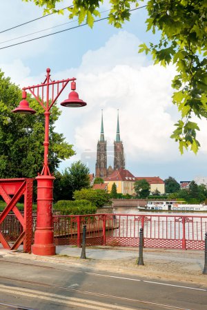Foto de Wroclaw Polonia. Farolas rojas en el puente de arena. Vista a la catedral de San Juan Bautista en la isla de Tumski. - Imagen libre de derechos