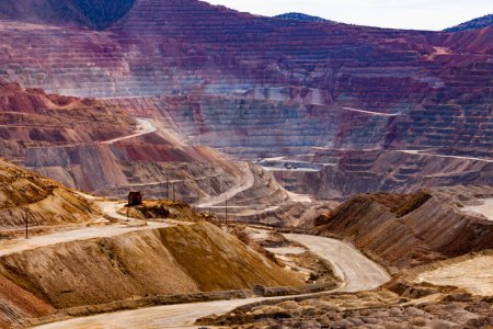 Paisaje industrial de terrazas de roca en capas coloridas y caminos de acarreo en explotación minera industrial de mina de cobre a cielo abierto profunda