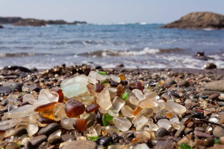 Pile of rounded glass shards or sea-glass of Fort Bragg, California, US with blurry Pacific Ocean background