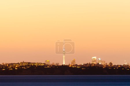 Photo for Distant skyline of Auckland City, New Zealand, with Sky Tower illuminated in twilight dusk after sunset - Royalty Free Image