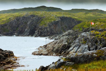 Photo for Maple Leaf Canadian Flag pole alone in barren coastal landscape of Newfoundland, NL, Canada - Royalty Free Image