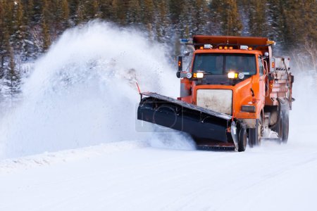 Snow plow truck clearing road after winter snowstorm blizzard for vehicle access