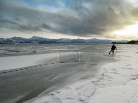 Téléchargez les photos : Un homme prudent vérifie la glace côtière dans le paysage hivernal pendant le gel du lac Laberge, Territoire du Yukon, Canada - en image libre de droit