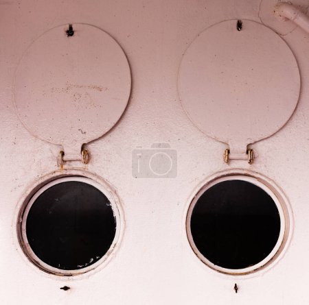 Photo for Abstract of two open bulleye portholes with round steel shutters onboard ship - Royalty Free Image