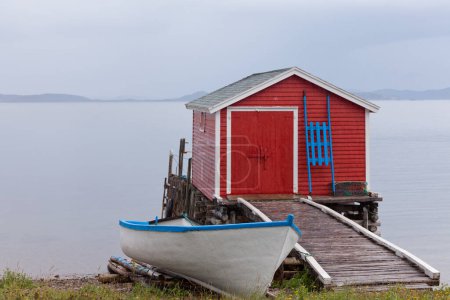 Photo for Beautiful red fishing shack and boat house at Newfoundland Atlantic ocean shore, NL, Canada - Royalty Free Image