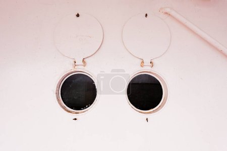 Photo for Abstract of two open bulleye portholes with round steel shutters onboard ship - Royalty Free Image