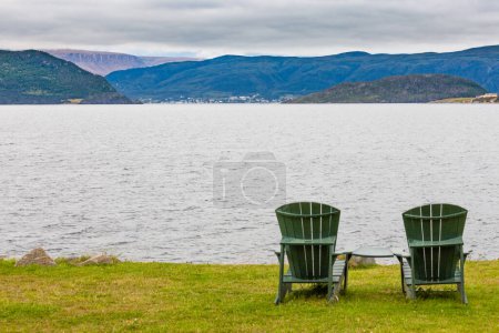 Photo for Green wooden Adirondack Chairs in beautiful coastal landscape of Gros Morne National Park, Newfoundland, NL, Canada - Royalty Free Image