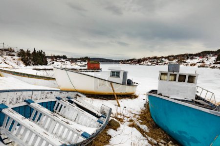 Photo for Small fishing boats beached for the winter at frozen North Atlantic Ocean bay, Newfoundland, NL, Canada - Royalty Free Image