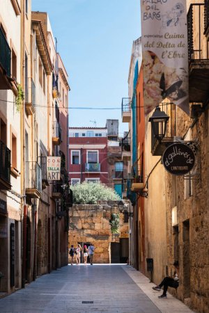Photo for TARRAGONA, SPAIN - AUGUST 6, 2022: Narrow street in the old town of Tarragona, a tourist port city by the Mediterranean Sea in the northeast of Spain. - Royalty Free Image