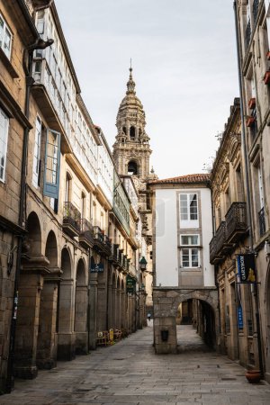 Photo for SANTIAGO DE COMPOSTELA, SPAIN - SEPTEMBER 17, 2022: Narrow busy street with cafes leading to the cathedral of Santiago de Compostela (ca. 1211) on the Plaza del Obradoiro square, a historial place of pilgrimage on the Way of St. James since the Middl - Royalty Free Image