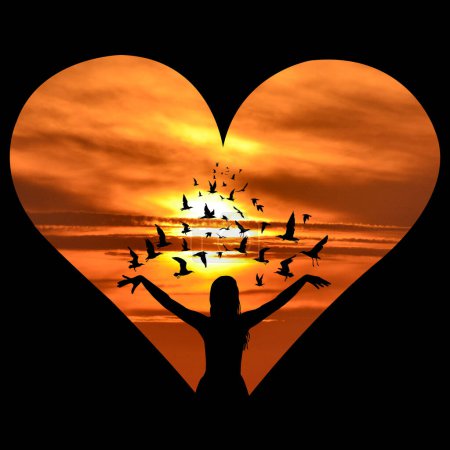 Téléchargez les photos : Coeur avec silhouette de femme avec des oiseaux volant autour d'elle au-dessus d'un coucher de soleil - en image libre de droit
