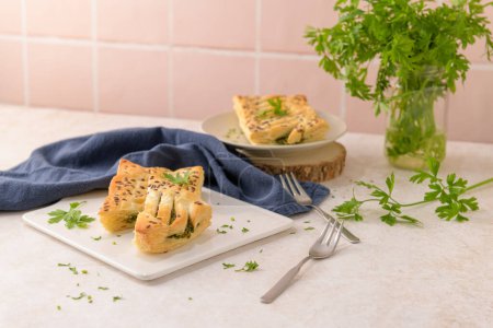 Photo for Spinach puff pastry with ricotta cheese and parsley leaves on white ceramic dishes in a kitchen counter top. - Royalty Free Image