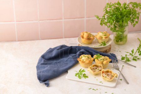 Photo for Chicken pies and parsley leaves on white ceramic dishes in a kitchen counter top. - Royalty Free Image