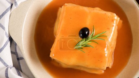 Photo for Traditional Portuguese snack food. Francesinha sandwich of bread, cheese, pork, ham, sausages, with tomato beer sauce and French fries. With beer and potatoes. On table. - Royalty Free Image