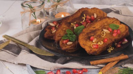 Photo for Traditional Christmas Rabanadas with pommegranate seeds, pine nuts and cinnamon. Spanish Torrijas or french toasts close up on the countertop. - Royalty Free Image