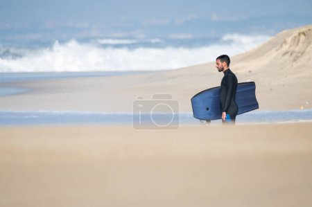 Photo for Bodyboarder watching the waves on a sunny day in Portugal. - Royalty Free Image