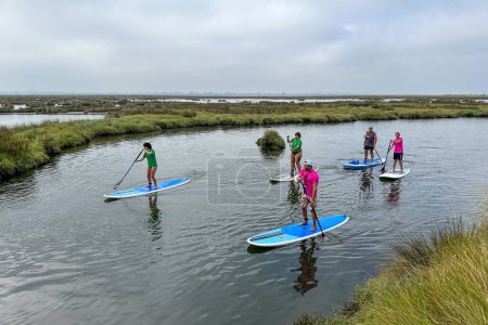 Foto de MURTOSA, PORTUGAL - CIRCA JUNIO 2023: Turistas practicando stand up paddle en un paseo por los canales de la Ría de Aveiro. El turismo es una actividad económica fundamental en Portugal. - Imagen libre de derechos