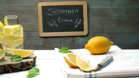 Lemon and lime slices in jars and straws in summer wooden background.