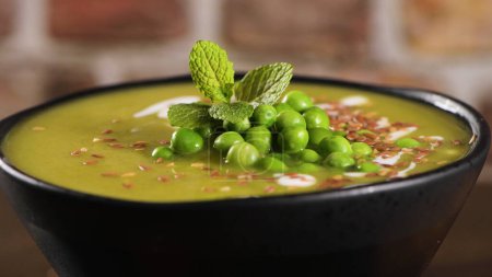 Soupe de pois verts avec graines de lin et de citrouille et graines de tournesol sur un comptoir de cuisine rustique
.