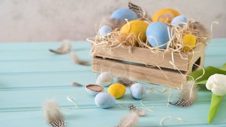 Foto de Huevos azules y blancos de Pascua en caja de madera y tulipanes blancos. - Imagen libre de derechos