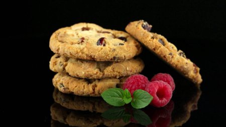 Téléchargez les photos : Fruits secs chips cookies et framboises isolés sur fond noir
. - en image libre de droit