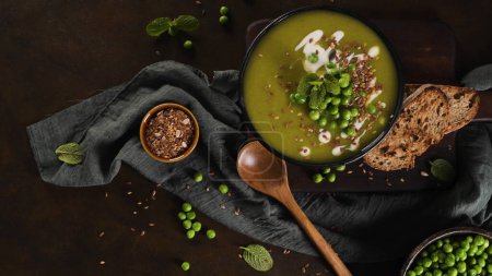Photo for Green pea soup with linseed and pumpkin and sunflower seeds on a rustic kitchen countertop. - Royalty Free Image