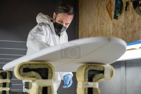 Fabrication de planches de surf, Shaper travaillant sur les détails de la carte. Concept de fabrication industrielle, professionnel qualifié, profession et emploi.