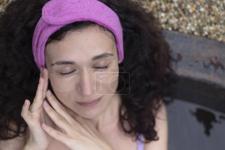 Une femme se relaxant dans une baignoire spa avec des patchs pour les yeux.