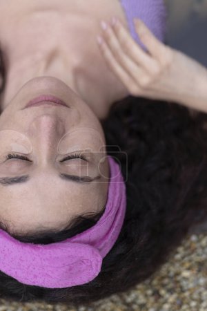 Una mujer con parches en los ojos acostada en la bañera de hidromasaje con los ojos cerrados en la relajación.