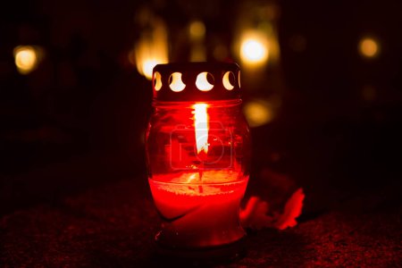 Téléchargez les photos : Bougie votive brûlant dans un cimetière la nuit - en image libre de droit