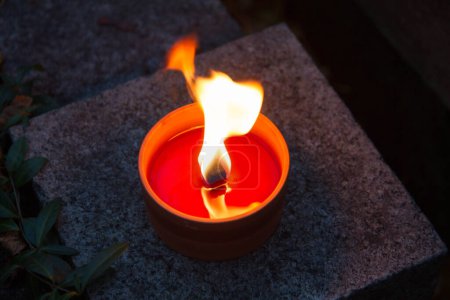 Votivkerze brennt nachts auf einem Friedhof