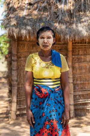 Photo for Belo Sur Tsiribihina, Madagascar - November 4. 2022: Malagasy woman in front of her hut with a traditionally painted face. Malagasy women paint their faces to protect their faces from the sun. - Royalty Free Image